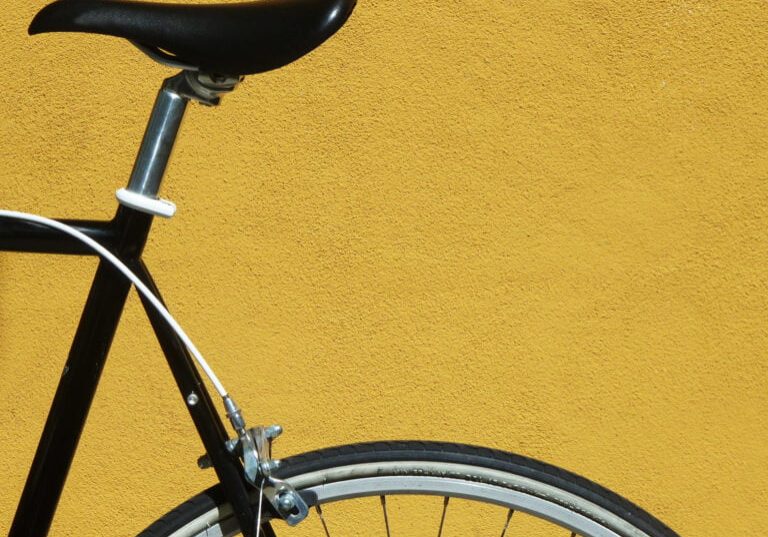 Detail of a black bicycle against a yellow wall